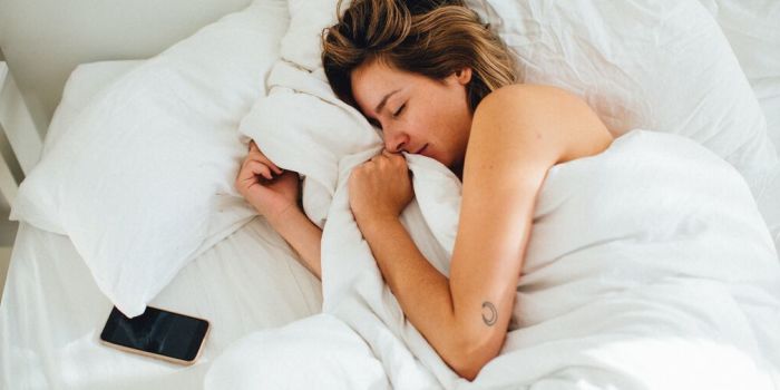 person sleeping by a mobile phone in bed