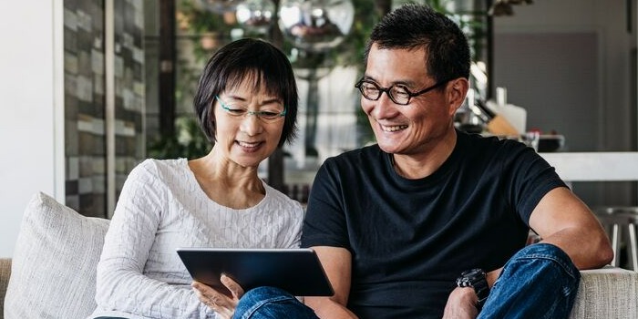 two people on a grey sofa with a tablet