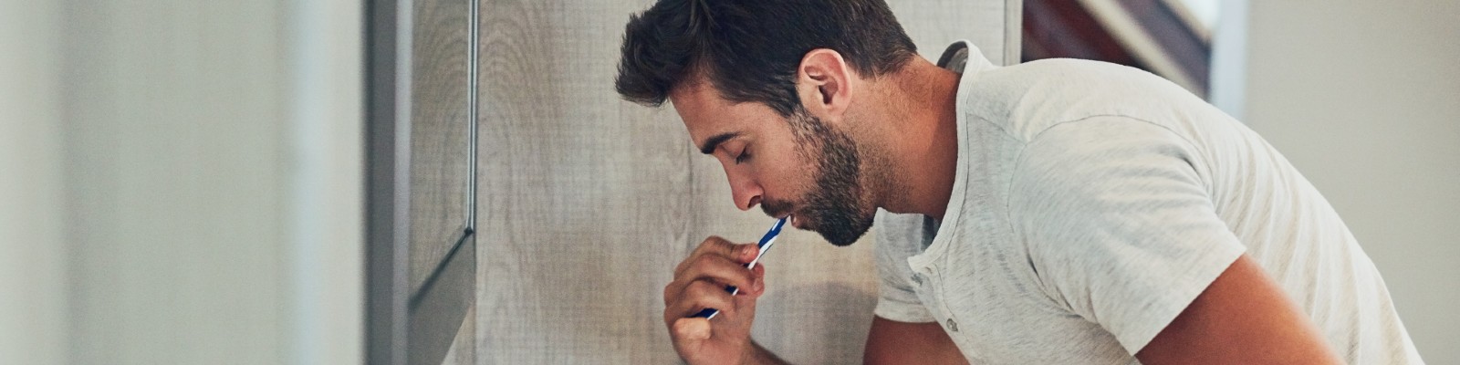 Man brushing teeth in bathroom mirror