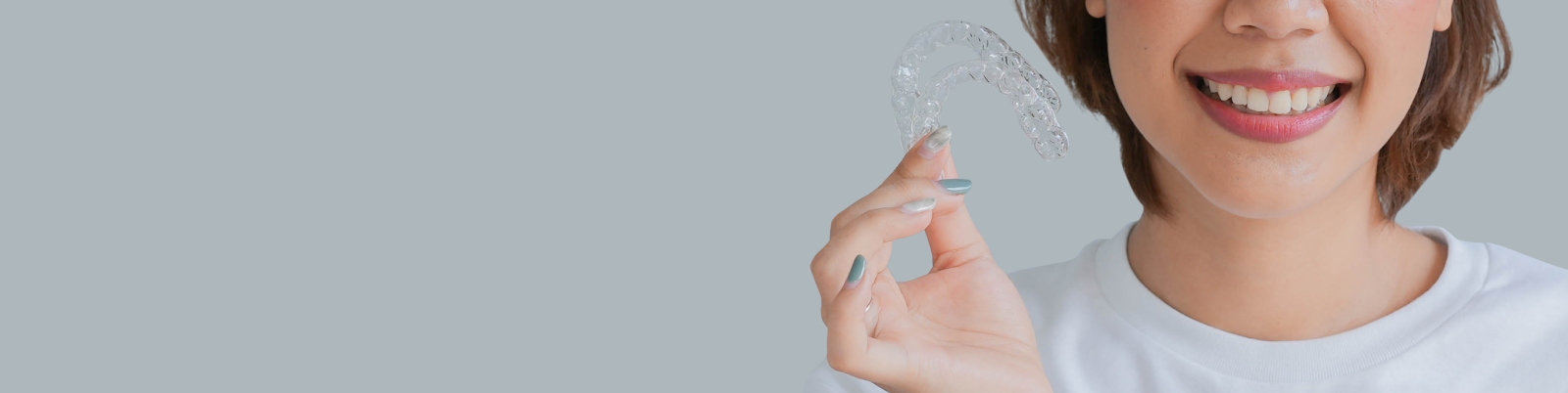 Smiling lady holding 2 clear aligners